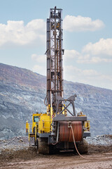 Large drill rig in an ore quarry. Preparation of boreholes for laying explosives in the quarry. Open-pit mining technologies.