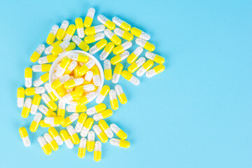 white container with yellow capsules or pills with white lozenges medicine on blue background