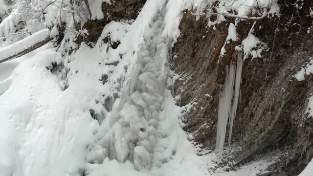 The popular Guk waterfall under Mount Khomyak in the Carpathians, Ukraine, in a snow-covered forest, the murmur of water and a quiet fall of snowflakes