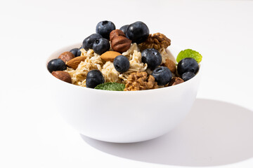 Bowl of oatmeal porridge with blueberry and nuts on white table. Healthy breakfast and diet food