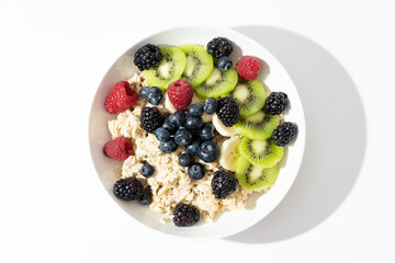 Organic food for healthy and dieting breakfast.Top view of bowl with oatmeal, fresh kiwi, blueberry on white background. top view.