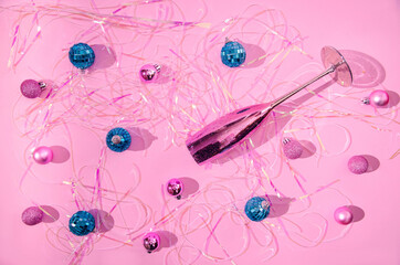 A shiny metallic Champagne glass, blue disco balls, pink Christmas balls and holographic tinsels on...