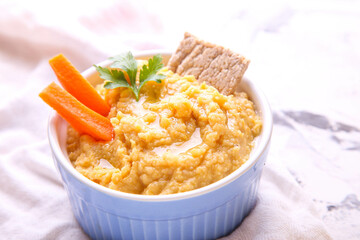 Hummus on a grey background with carrots, lemon and spices