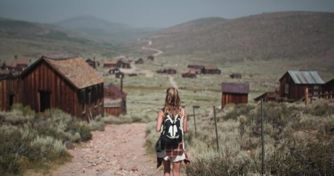 Female hiker with backpack exploring the gold mining ghost town of Bodie, California in the summer