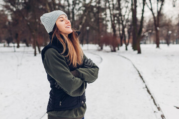 Young runner having rest after training in snowy winter park. Woman breathing outdoors. Workout