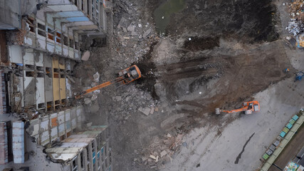 Excavator for dismantling buildings, using a special claw, dismantles a multi-storey building. View from above