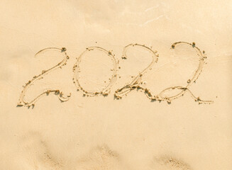 inscription 2022 on yellow sand close up.