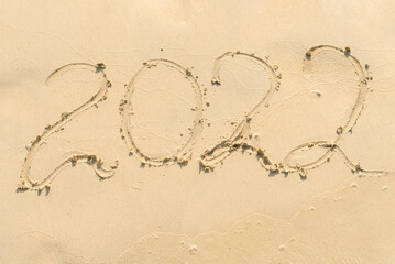 handwritten lettering 2022 on sandy beach