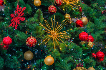 Different red and yellow multicolored new year decorations on green christmas tree