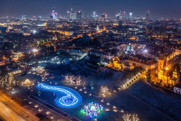 Warszawa, multimedialny park fontann ozdobiony świątecznymi dekoracjami i oświetleniem, widok z lotu ptaka na odległe centrum miasta zimą - obrazy, fototapety, plakaty