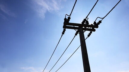 Silhouette of electric wires on concrete poles. High-voltage cables on poles contrast the bright...