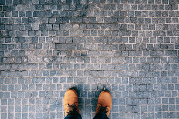 Male feet in brown boots stand on the cobblestones. Close-up