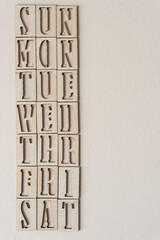 days of the week (sun to sat) in wooden stencil font on textured ivory paper