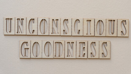 the expression "unconscious goodness" in wooden stencil font on paper