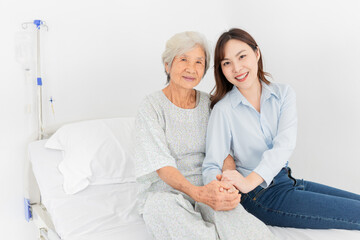 Obraz premium old asian patient sick and admit in hospital, young asian female visiting old female, they holding hands together, they feeling happy and smile, elderly healthcare