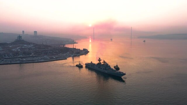 December 2021 - Vladivostok, Russia - A Pacific Fleet warship is moored in the Golden Horn in Vladivostok. View from above. A military ship in the roadstead against the backdrop of a bright dawn.
