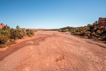 Dry riverbed amidst historic fort structures with bushes on deserted land against blue sky