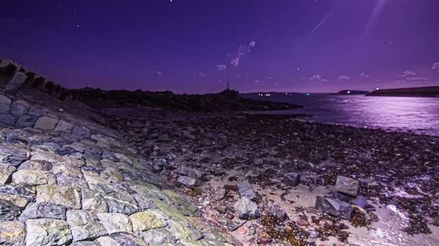 night ebbing tide in the sea channel of Guernsey island, Bailiwick of Guernsey. Moonlight reflecting over ocean surface