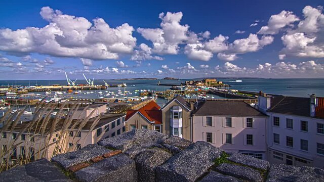 Evening timelapse view over a small town beside the port in Guernsey island in the English Channel off the coast of Normandy, part of the Bailiwick of Guernsey.