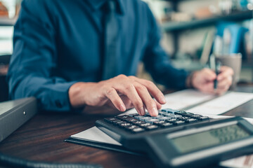 Financial businessman working on desk office using a calculator to calculate calculating corporate...