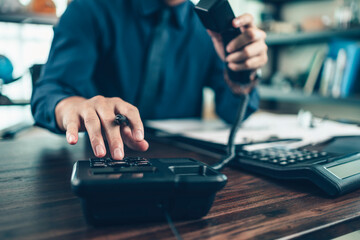 Fototapeta premium businessman dialing desk phone in the office. Telephone dialing ,contact and customer service.