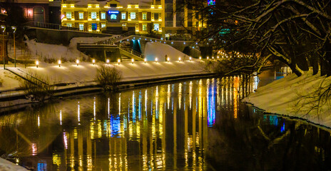 Fototapeta na wymiar The embankment by the river in the evening with bright lights.