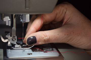 Fototapeta na wymiar Woman's hand threading sewing machine