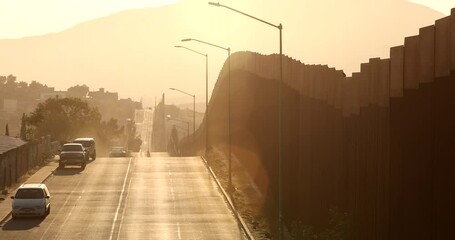 Tecate, Baja California, Mexico - September 14, 2021: Late afternoon sun shines on the USA Mexico border wall as it winds through Tecate.