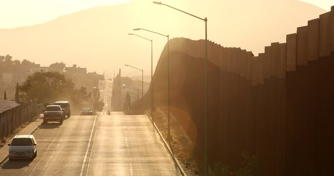 Tecate, Baja California, Mexico - September 14, 2021: Late afternoon sun shines on the USA Mexico border wall as it winds through Tecate.