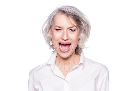 Photo of mature beautiful grey-haired woman yelling and screaming loudly with a wide open mouth with an angry expression isolated on white background