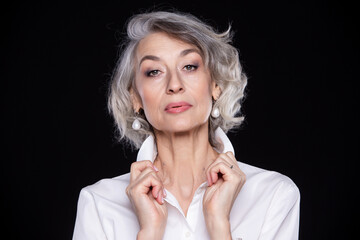 A picture of an adult mature self-confident gray-haired woman isolated on a black background