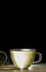 infusion of tea, cannabis herb, in a glass cup on black background.
