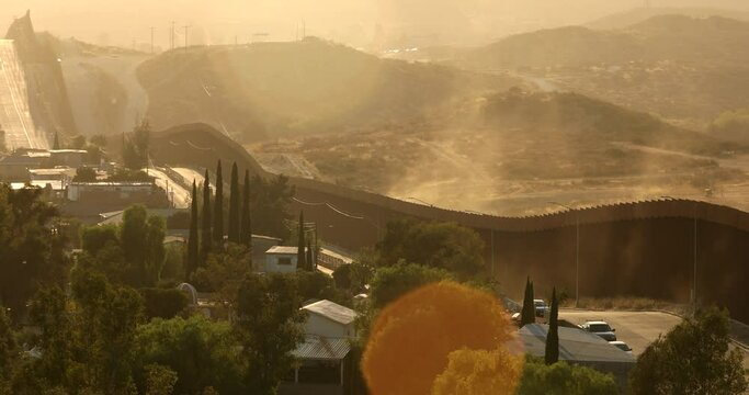 Tecate, Baja California, Mexico - September 14, 2021: Late afternoon sun shines on the USA Mexico border wall as it winds through Tecate.