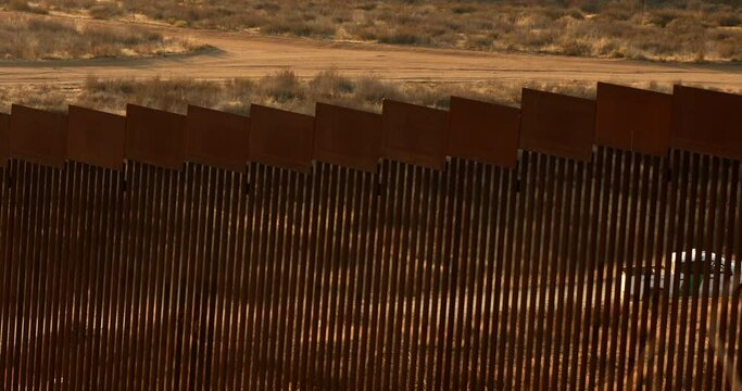 Tecate, Baja California, Mexico - September 14, 2021: Late afternoon sun shines on the USA Mexico border wall as it winds through Tecate.