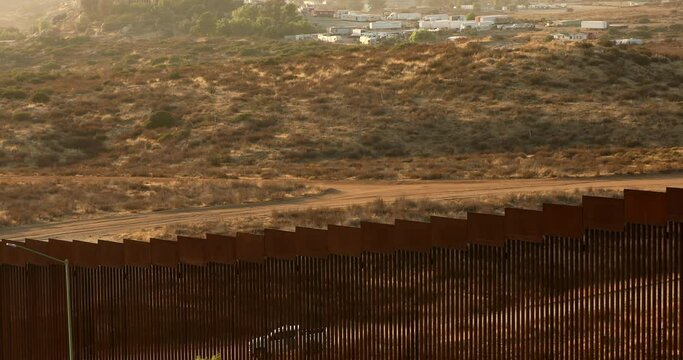 Tecate, Baja California, Mexico - September 14, 2021: Late afternoon sun shines on the USA Mexico border wall as it winds through Tecate.