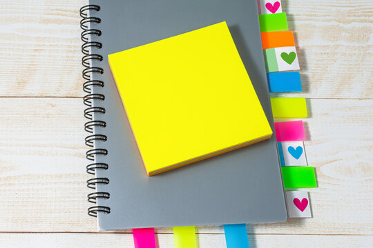 Top view of a gray notepad with colorful bookmarks and a blank yellow notepad. Business planning or training concept