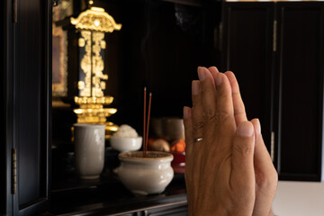 仏壇の前で手を合わせる男性