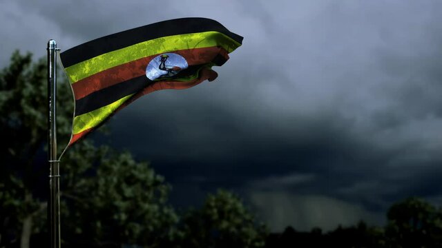 waving Uganda flag for national celebration on dark storm cumulus clouds