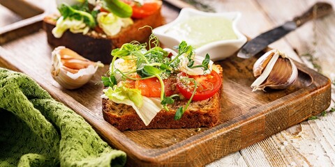 Food banner. Toast with salted fish, cheese, eggs, onion rings and salad. Appetizing canapes or sandwiches with smoked salmon. Traditional Delicious breakfast or snack on a wooden background