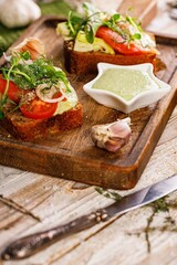 Appetizing lunch or snack. Canapes or sandwiches with smoked salmon. Toast with fish, soft cheese, eggs, onion rings and fresh salad. Garlic sauce with cheese and herbs. Vertical shot. Copy space