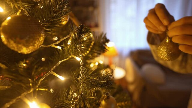 close up slow motion of beautiful smiling Woman decorates christmas tree at home with bulbs. making nice festive athmosfere in home interior and celebrating xmas and happy new year.