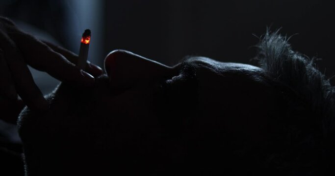 depressed man smoking  cigarette in dark