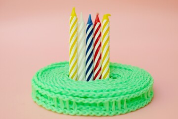 Colourful candles isolated in the green rope on pink background. Birthday,Christmas and special greetings concept. © Hari