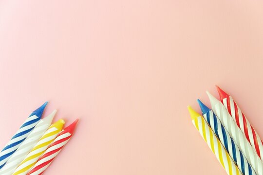 Colourful candles isolated in the green rope on pink background. Birthday,Christmas and special greetings concept.