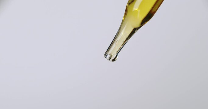 A simple pipette dropper with yellow liquid and a bright white background.