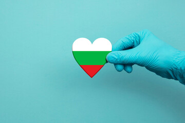 Medical workers hand wearing surgical glove holding Bulgaria flag heart