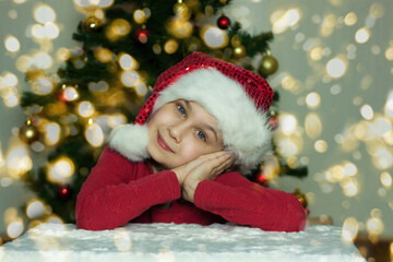 Portrait of a smiling girl in a Santa hat under the Christmas tree
