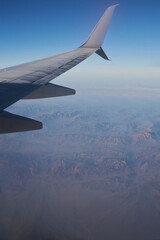 Beautiful high angel view at the mountains through the porthole of the plane. Travel cocept