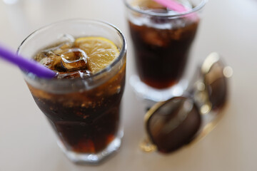 Pair of glasses filled with coca cola with lemon and ice cubes, cooling summertime drinks