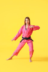 Fototapeta na wymiar Young woman practicing karate on color background